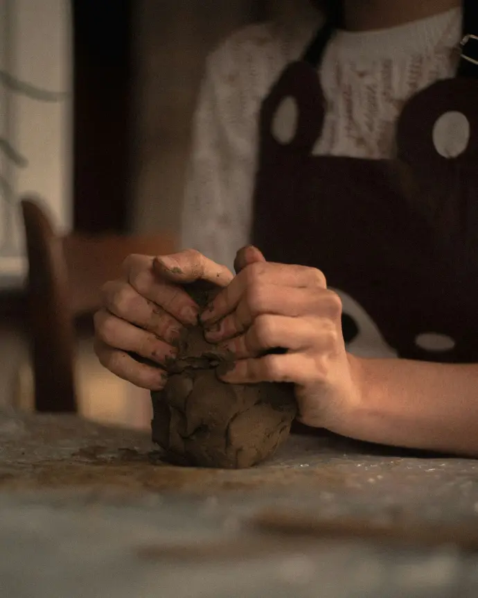 A person shapes clay with their hands.